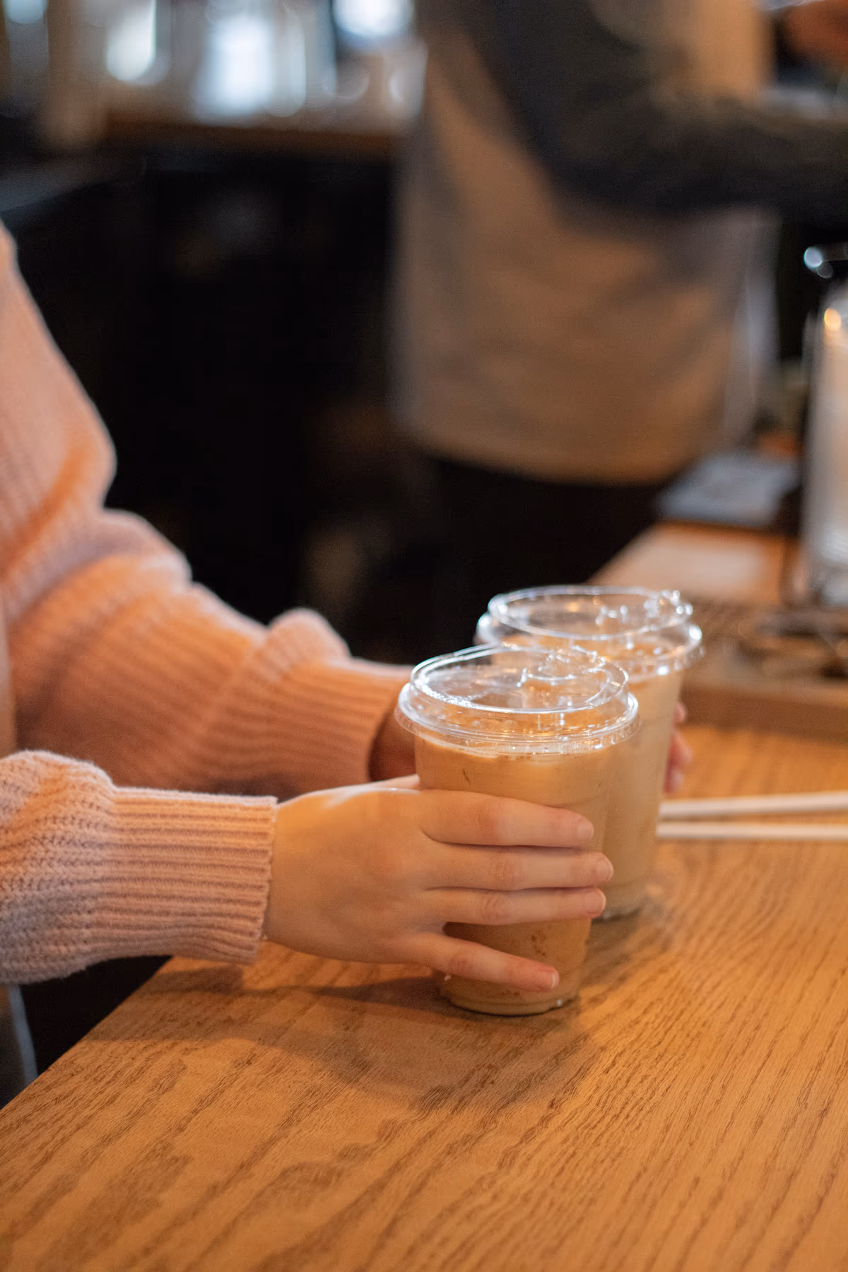 Customer holding two iced coffees at the counter at Old Pine Coffee Roasters