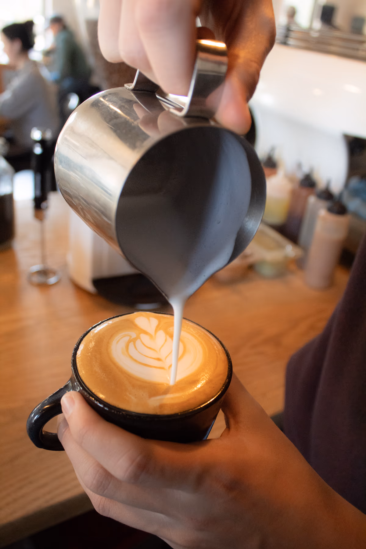 Barista pouring latte art into a cup at Old Pine Coffee Roasters