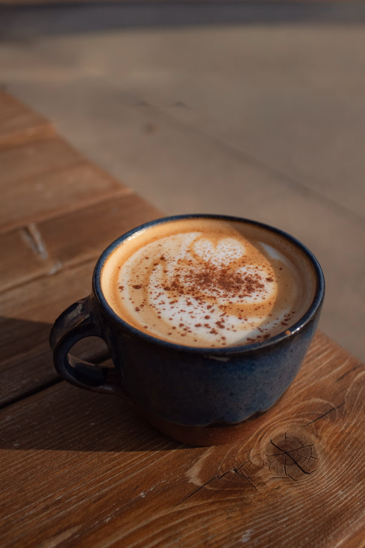 Latte with cinnamon dusting and latte art on a wood table at Old Pine Coffee Roasters