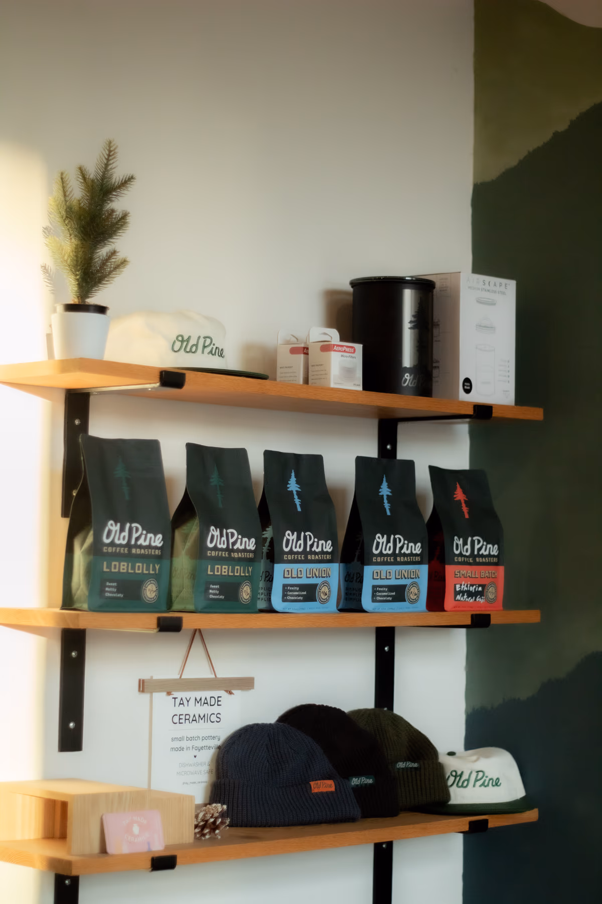 Old Pine Coffee Roasters merch shelf with coffee bags, hats, and branded goods