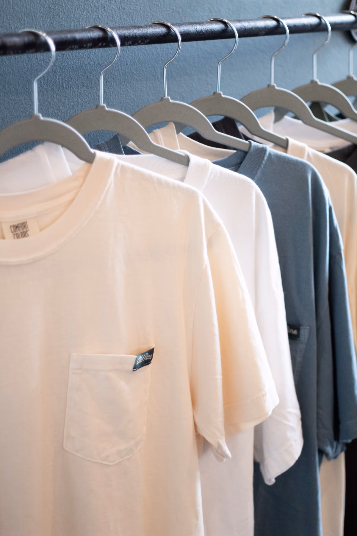 Old Pine Coffee Roasters branded t-shirts hanging on a merch rack